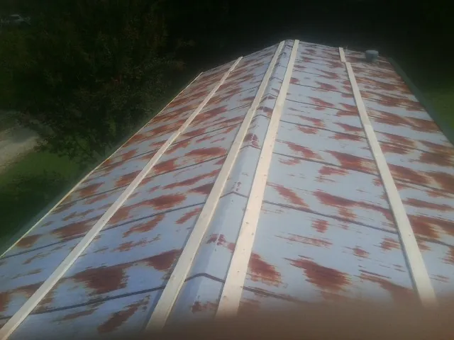 Rusted metal roof panels with new wood purlins before replacement in Eastlake Weir