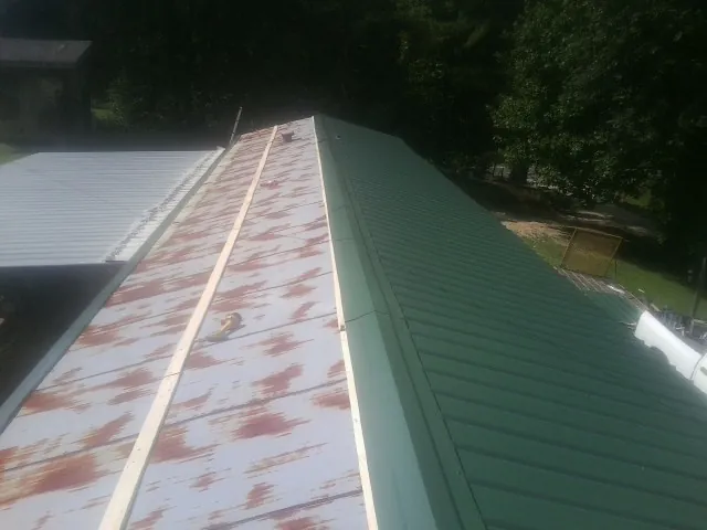 Old rusted panels beside newly installed green metal roofing — Wind Damage Roof Repair by Roofing Brothers in Eastlake Weir