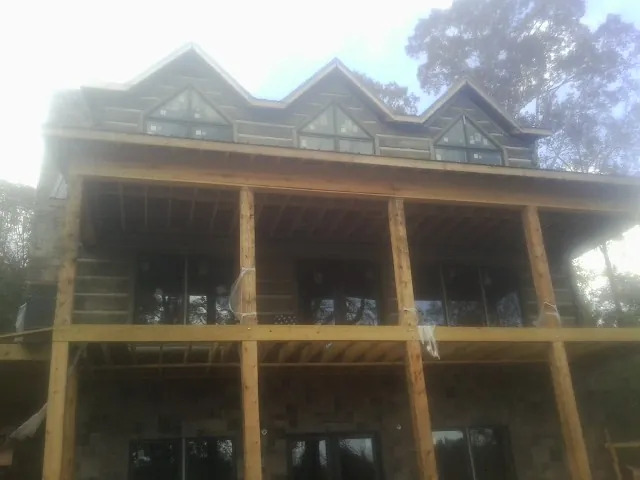 Dormers and porch framing on a large log home under construction — Roof Coating work by our crew in Eastlake Weir