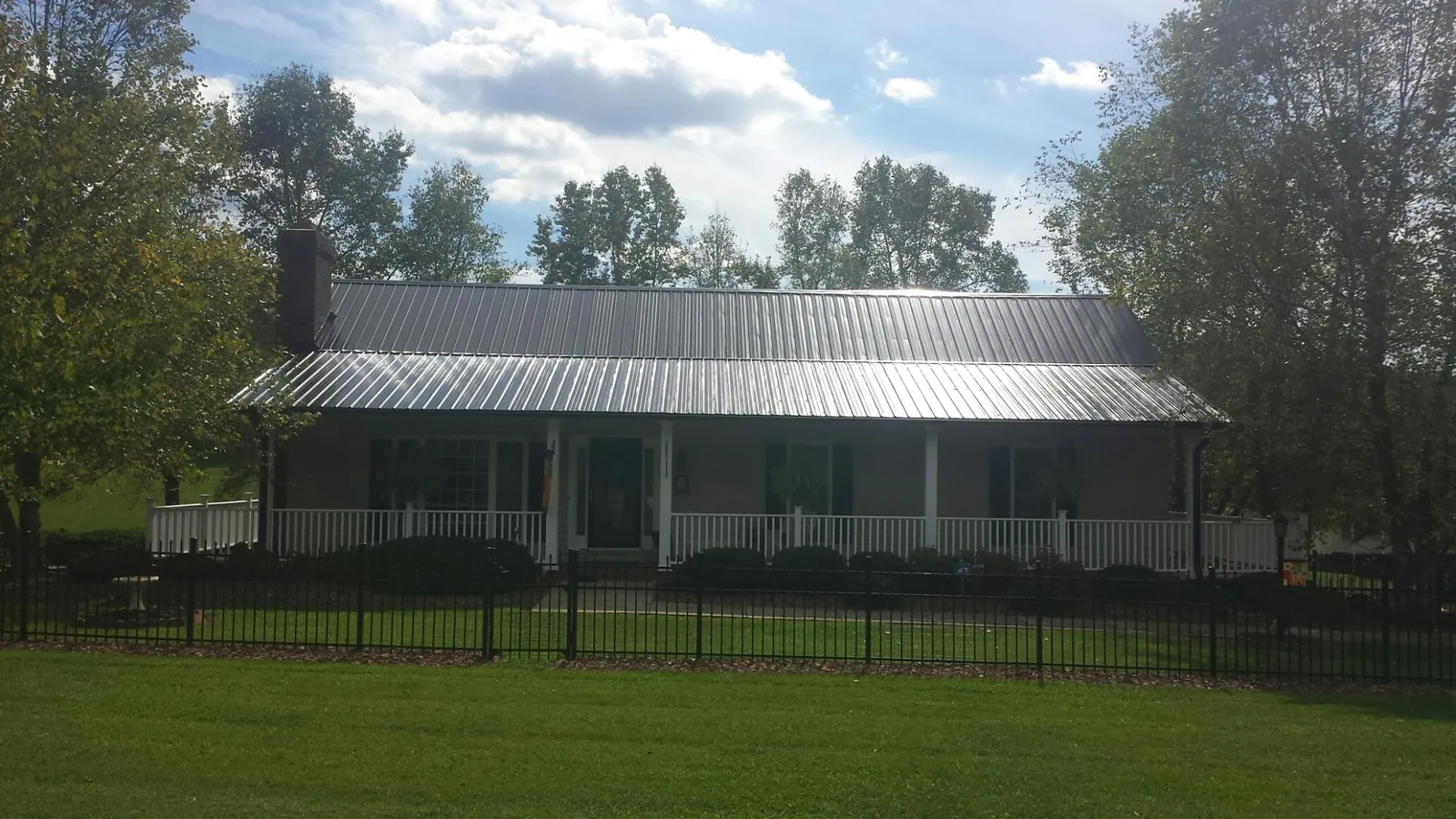 Gray metal roof on a brick ranch with a full width front porch — Gutter Guard Installation work by our crew in Eastlake Weir
