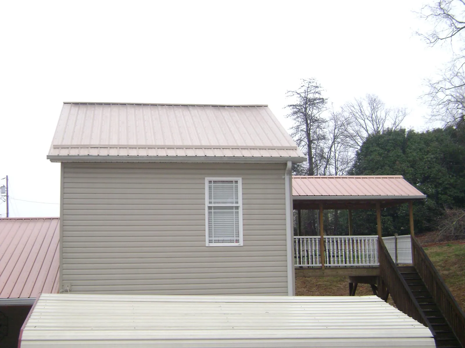 Tan metal roofs on a two story addition and attached porch, from a Roof Replacement job in Eastlake Weir