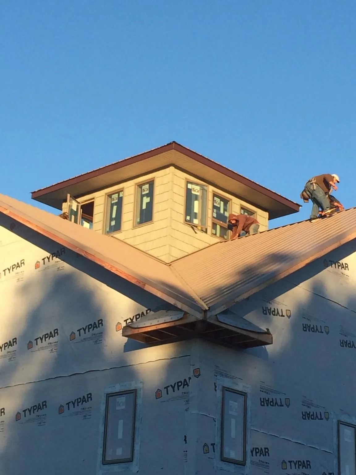 Roofers working around a rooftop cupola on a new metal roof at sunset — Roof Waterproofing in Eastlake Weir by Roofing Brothers
